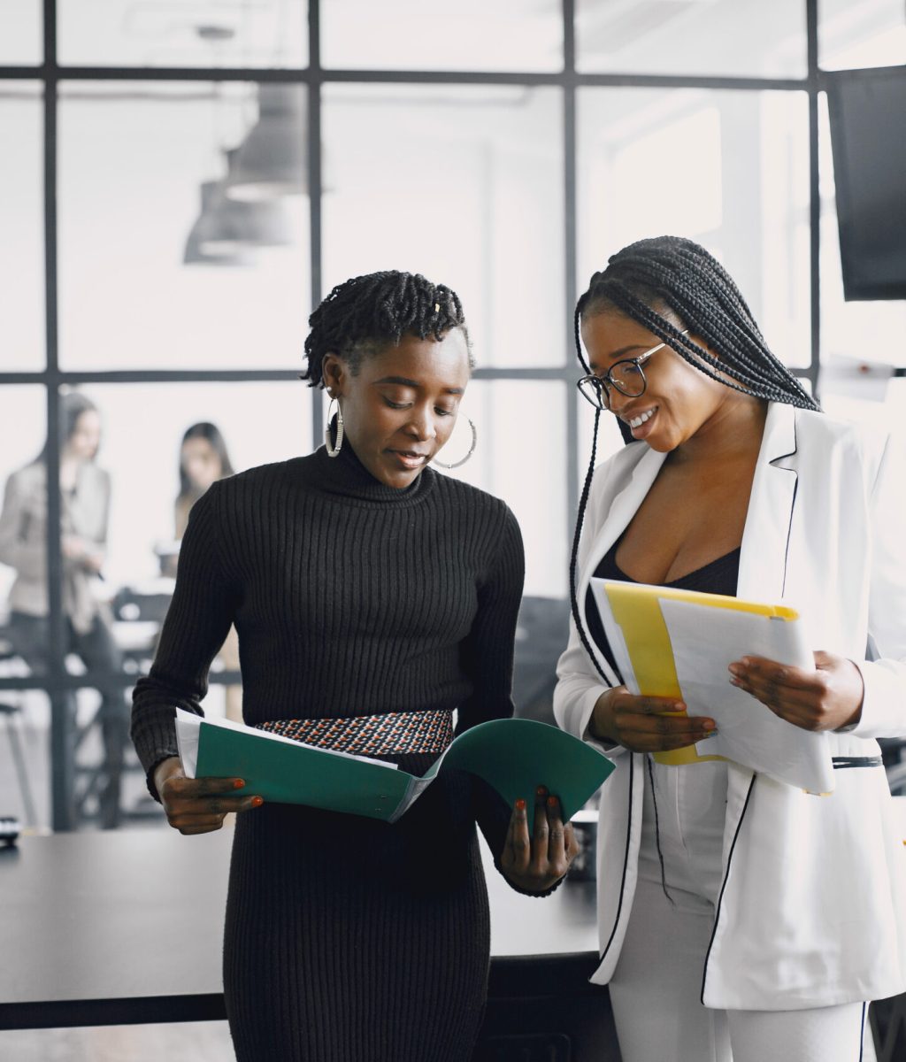 Business women talking near the desk during a coffee break in the hallway of the big corporation